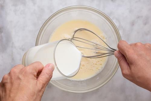ガラスの鉢の中に生卵を混ぜた牛乳を入れたグラスを持つ