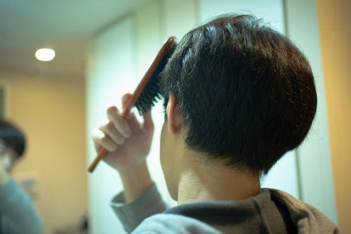 鏡の前で髪をとかす男性の写真