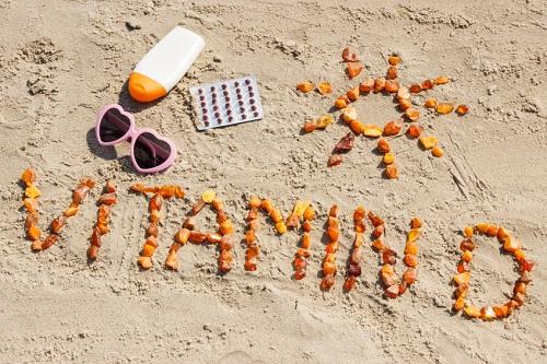 ビタミン D の碑文製オレンジ色の石と砂のビーチで休暇の時間の概念とビタミン D 欠乏症の予防の日光浴用アクセサリー