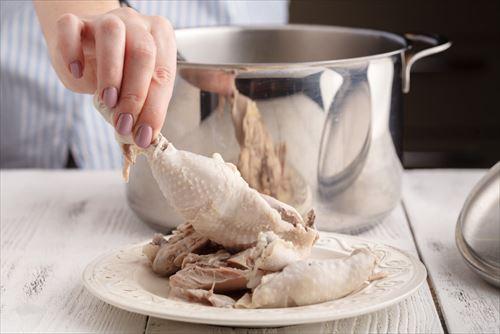 鍋から茹でた鶏肉を取り出す様子