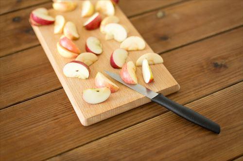 木製のまな板にスライスしたリンゴとナイフ
