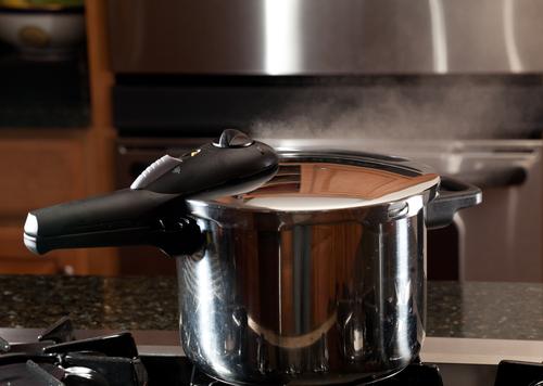 モダンなキッチンの反射と圧力鍋の蓋から逃げる蒸気