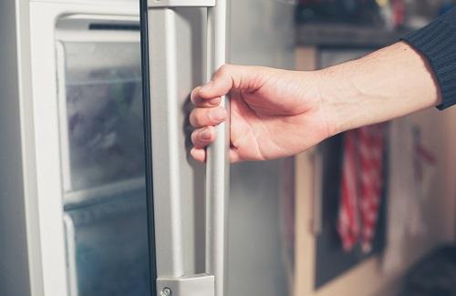 冷凍庫のドアを手で開ける