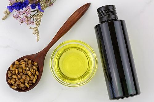 有機コールドプレスグレープシードオイルのボトルと木のスプーンで乾燥したブドウの種子と透明なボウル