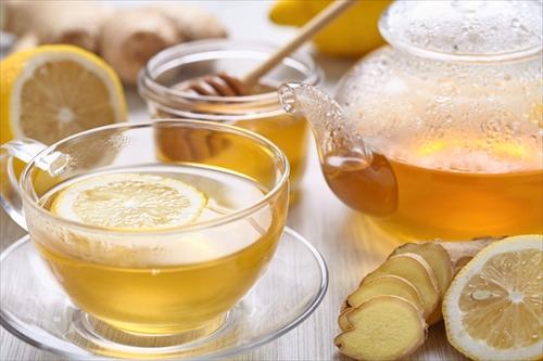 木製テーブルの上のレモンと蜂蜜生姜茶のカップ
