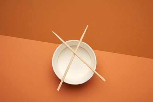 カップ麺の空き容器と_印に置かれた箸の画像