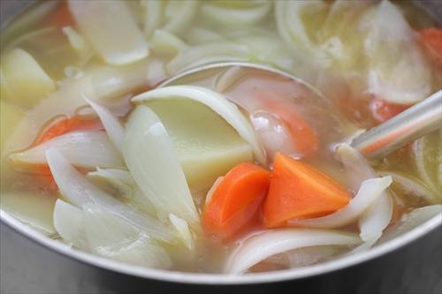 鍋で煮ている人参や玉ねぎやジャガイモなどの野菜