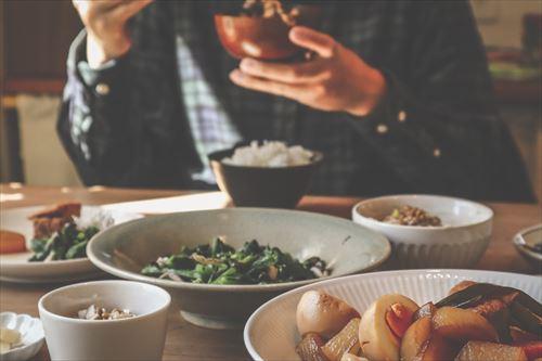 男性が味噌汁茶碗を持つ食事風景