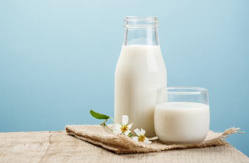 青の背景に木のテーブルの上に牛乳の瓶と牛乳のガラス