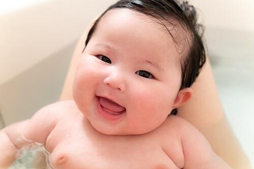 笑顔でお風呂に入っている赤ちゃんの写真