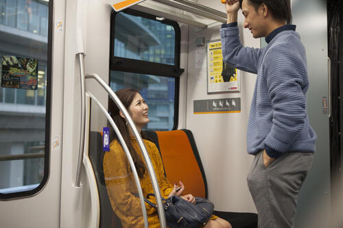 電車に乗っている妊婦さんとその旦那さんのイメージ写真