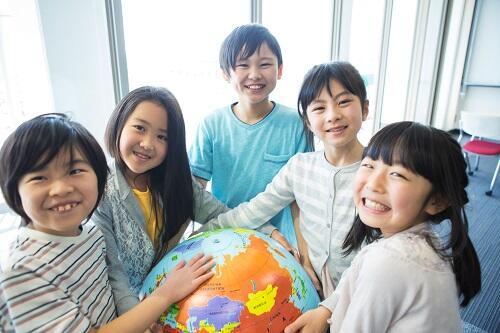 地球儀を抱えて微笑む小学生くらいの子どもたちの写真