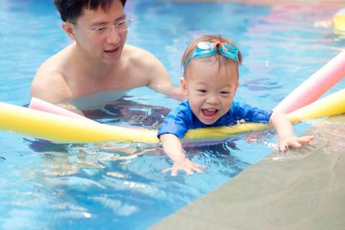 パパとプールで遊ぶ笑顔の子どもの写真