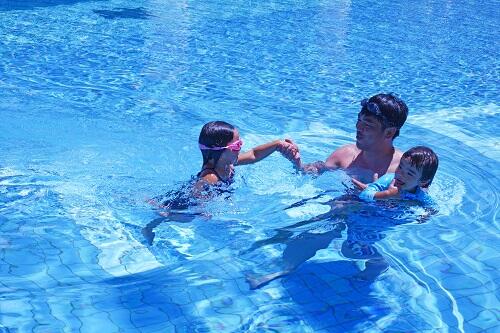 パパとプールで遊ぶ二人の子どもの写真