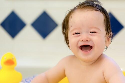 笑顔でお風呂ではしゃいでいる元気いっぱいの赤ちゃんの写真