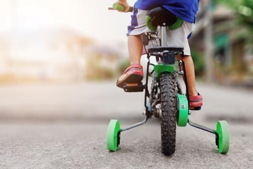 補助輪つきの自転車に乗っている子どもの写真