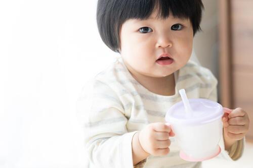 湯冷ましを飲もうとしている赤ちゃんのイメージ写真