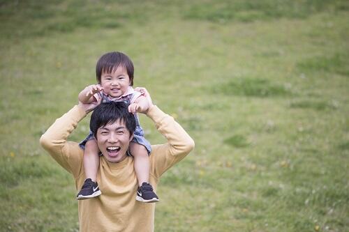 子どもをおんぶしている笑顔のお父さんの写真