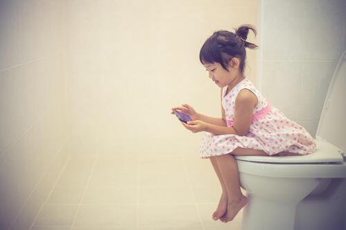 大人と同じトイレに座っている子どもの写真