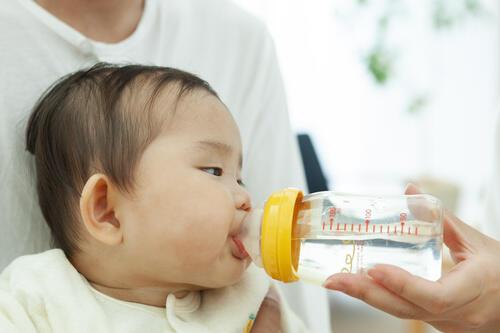 哺乳瓶で湯冷ましを飲む赤ちゃんのイメージ写真