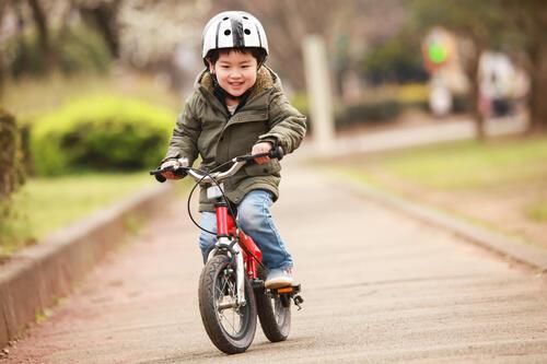 自転車の練習をする笑顔の子どもの写真