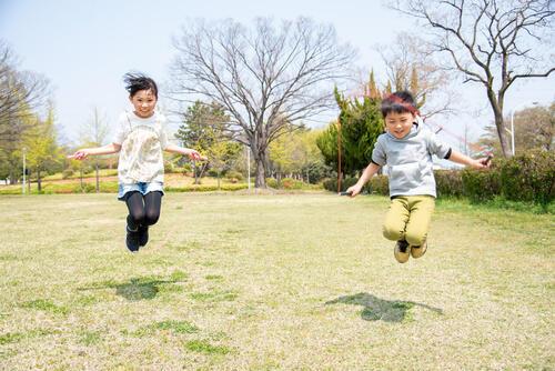 元気に縄跳びをする小学生の男の子と女の子の写真
