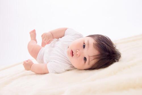 仰向けになりながらこちらを見つめる赤ちゃんの写真
