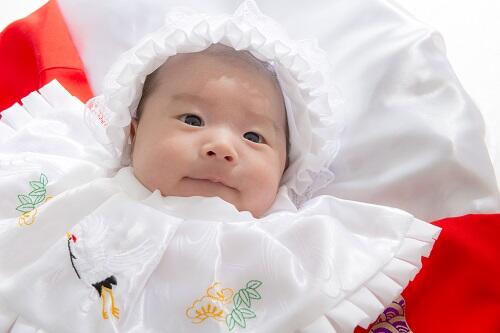 紅白の敷物の上で笑顔を浮かべる新生児の写真