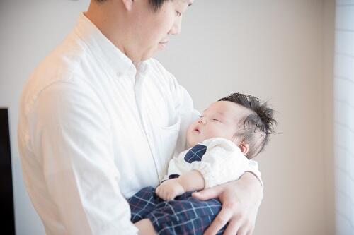 パパが抱っこしている腕の中で眠っている赤ちゃんの写真
