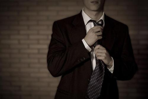 スーツのネクタイを締めようとしている男性