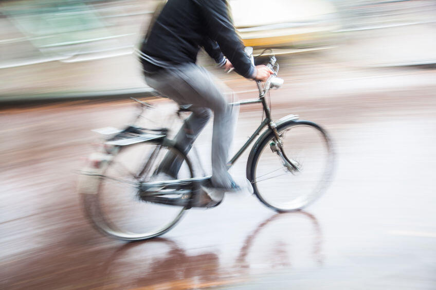 雨の日に自転車を運転する男性