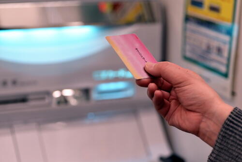 ATMの前でカードを手に持つ人の写真
