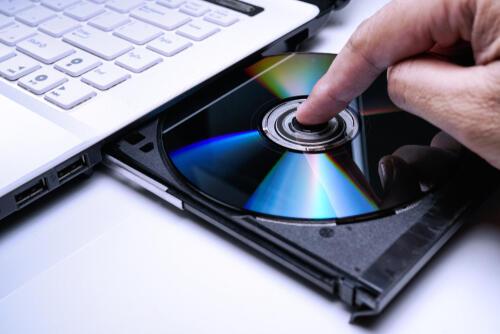 DVDをノートパソコンのドライブに挿入しようとしているところの写真