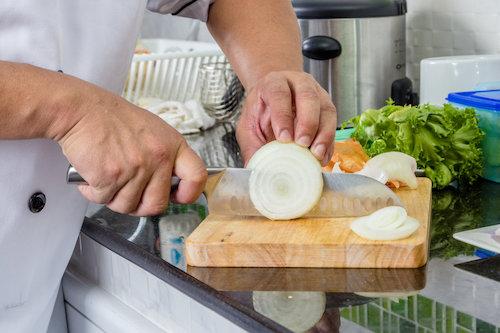 食材が切りやすい木製のまな板で調理をするシェフの写真