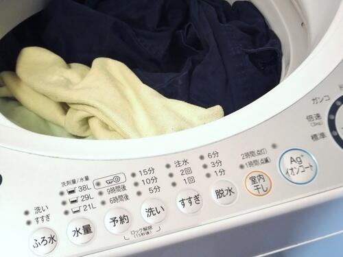 洗濯物が詰まった縦型洗濯機の写真