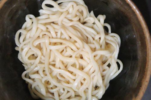 耐熱容器の中にうどんと調味料を加えて電子レンジで加熱する