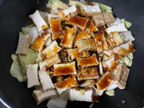 白菜を炒めたフライパンに、厚揚げ、調味料、ショウガを投入