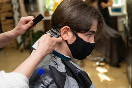 美容院で刈り上げてもらっているマッシュヘアの男性のイメージ写真