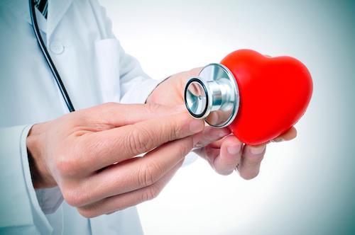 心臓に聴診器を当てて心音や拍動を確認している医師のイメージ写真