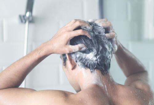 シャンプーで頭を洗う男性の写真