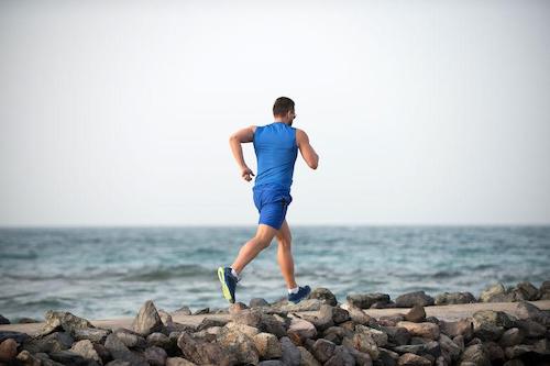 海岸沿いをジョギングする男性の写真