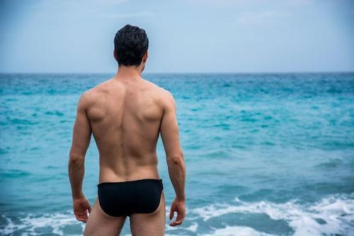 海を眺める引き締まったお尻の男性の写真