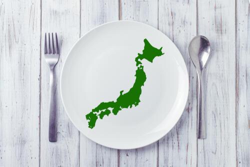 木の背景と日本地図が描かれたお皿、フォークとスプーンの写真