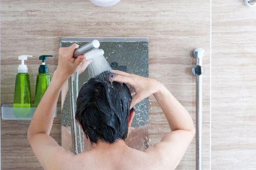 シャワーで頭を流す男性の後ろ姿の写真