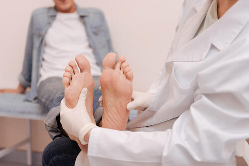 皮膚科で足の裏を診断してもらっている男性のイメージ写真