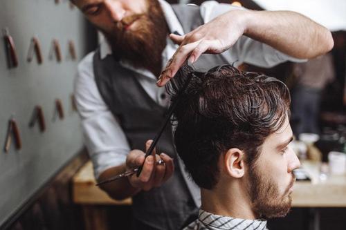 美容院で髪をカットしてもらっている男性の写真