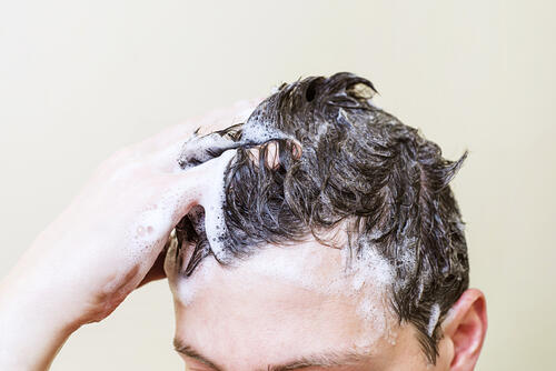 シャンプーで頭を洗っている男性