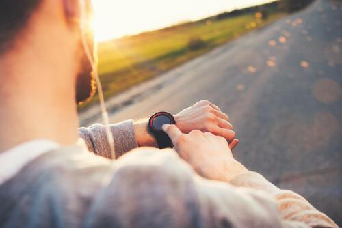 ウォーキング前に時計を見ている男性のイメージ写真