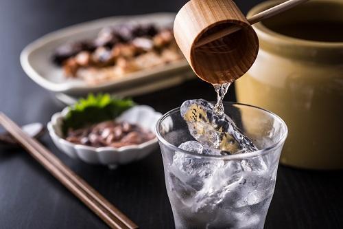 和食とグラスに柄杓で芋焼酎を注いでいるところのイメージ