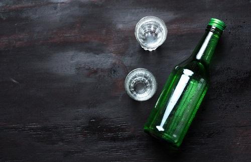 ショットグラスに入ったチャミスルと緑色の瓶を上から撮影した写真